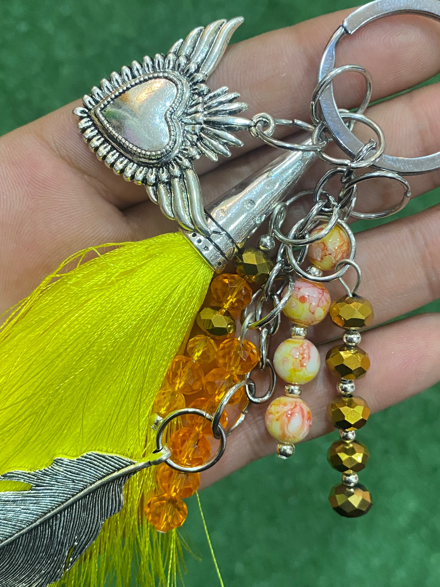 Llavero en tonos amarillos con corazón y pluma plateados
